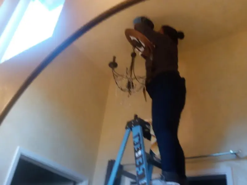 Electrician installing a chandelier in a Anthem residence
